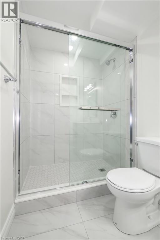 Glass-enclosed shower featuring white subway tile, a built-in shower niche, and a honeycomb-patterned shower pan - 67 Hollyridge Crescent Unit# Lower, Kitchener, ON - Indoor Photo Showing Bathroom