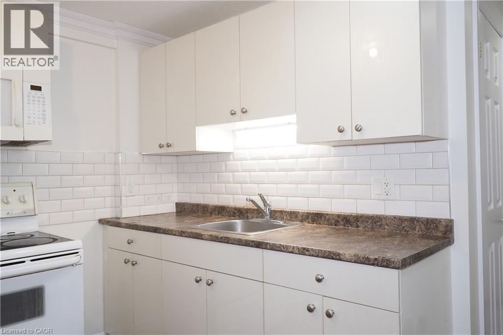 Kitchen featuring white cabinetry with silver hardware, under-cabinet lighting, a subway tile backsplash, and dark stone-finish countertops - 67 Hollyridge Crescent Unit# Lower, Kitchener, ON - Indoor Photo Showing Kitchen