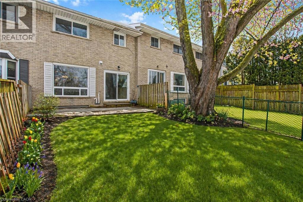 Expansive backyard featuring a manicured lawn, a mature deciduous tree, and a stone patio - 104 Ralgreen Crescent, Kitchener, ON - Outdoor