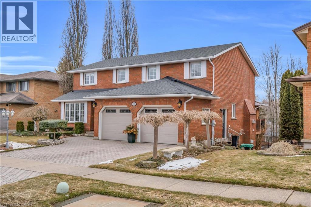 Brick two-story residence featuring a two-car garage with arched windows, a bay window with white framing, and a paved driveway - 228 Michener Crescent, Kitchener, ON - Outdoor