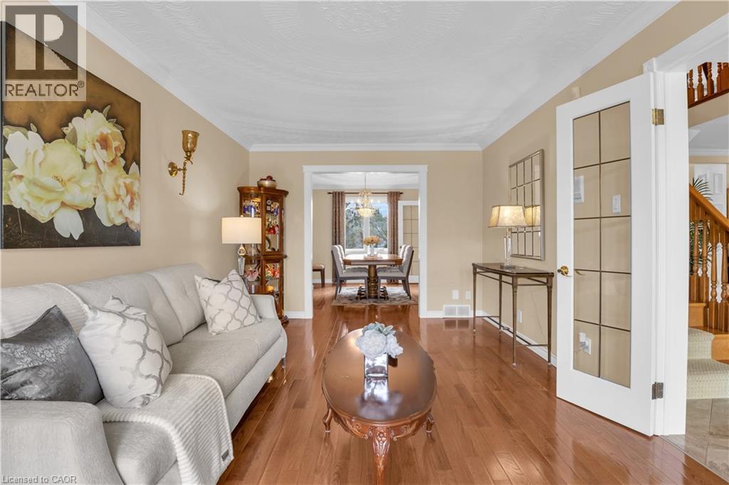 Living room featuring wood-finish flooring, crown molding, and an open entryway to the dining area - 228 Michener Crescent, Kitchener, ON - Indoor Photo Showing Living Room