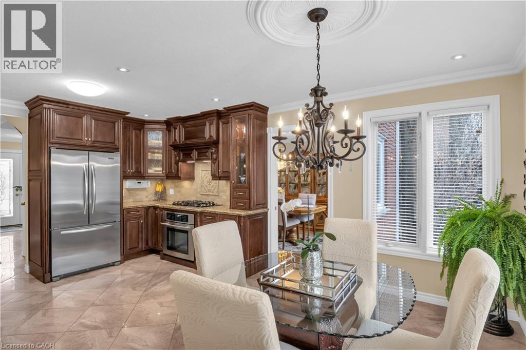 Kitchen featuring dark wood cabinetry, stainless steel appliances, and a tile backsplash - 228 Michener Crescent, Kitchener, ON - Indoor