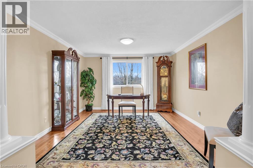 Neutral-toned interior room featuring wood-finish flooring, white baseboards, and crown molding - 228 Michener Crescent, Kitchener, ON - Indoor Photo Showing Other Room
