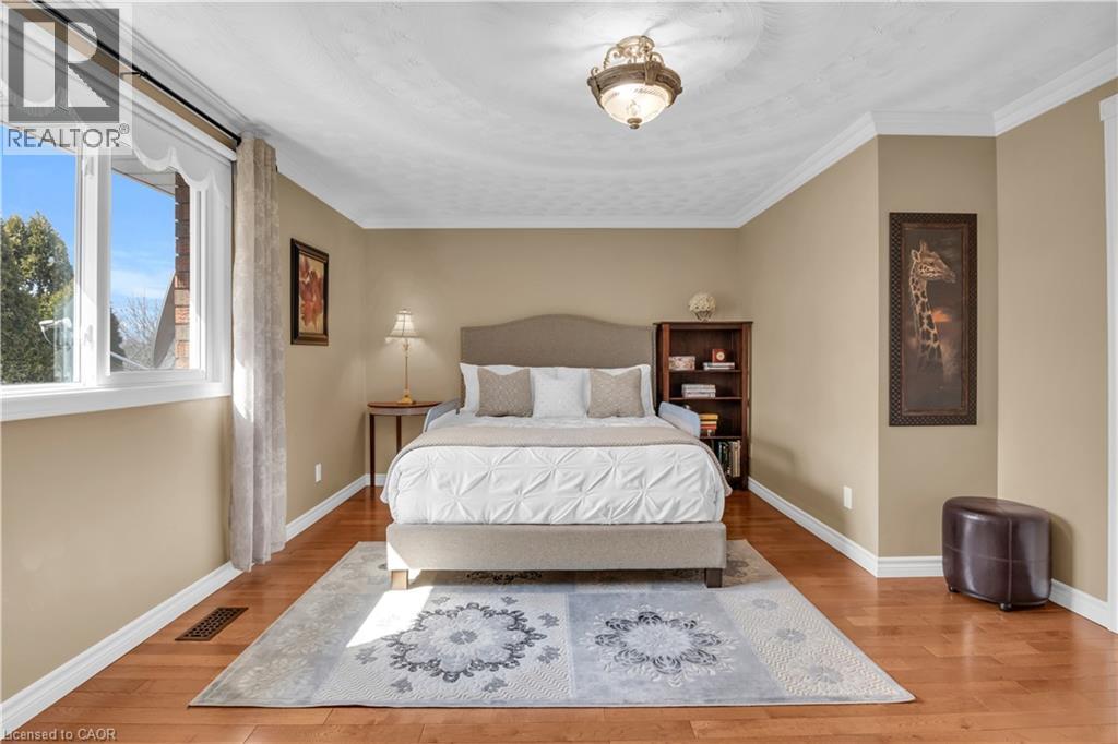 Spacious room featuring wood-finish flooring, ample natural light from a large window, crown molding, and a built-in ceiling fixture - 228 Michener Crescent, Kitchener, ON - Indoor Photo Showing Bedroom