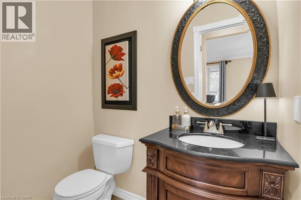 Bathroom featuring a dark wood-finish vanity with carved details, a dark countertop, and an oval mirror with a decorative frame - 228 Michener Crescent, Kitchener, ON - Indoor Photo Showing Bathroom