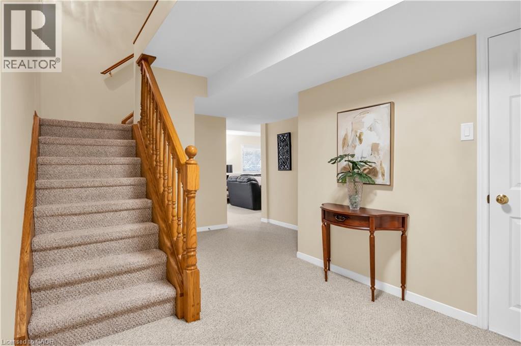 Carpeted staircase with wood banister and handrail, neutral wall tones, and white trim - 228 Michener Crescent, Kitchener, ON - Indoor Photo Showing Other Room