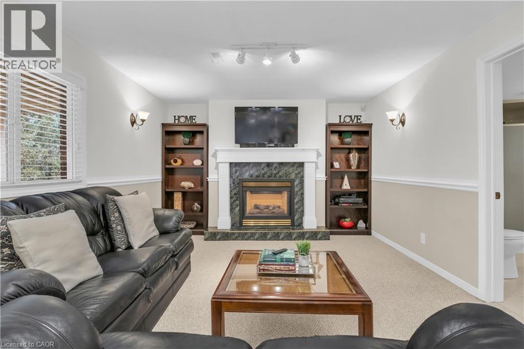 Carpeted living area featuring a fireplace with a dark green tile surround and white mantel - 228 Michener Crescent, Kitchener, ON - Indoor Photo Showing Living Room With Fireplace