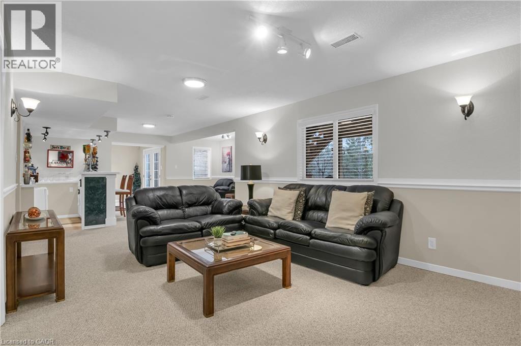 Spacious recreation room featuring neutral carpeting and a built-in bar with a stone-finish countertop - 228 Michener Crescent, Kitchener, ON - Indoor Photo Showing Living Room