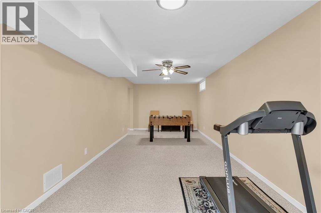 Spacious recreation room featuring light-colored carpeting, neutral painted walls, and white baseboards - 228 Michener Crescent, Kitchener, ON - Indoor Photo Showing Gym Room