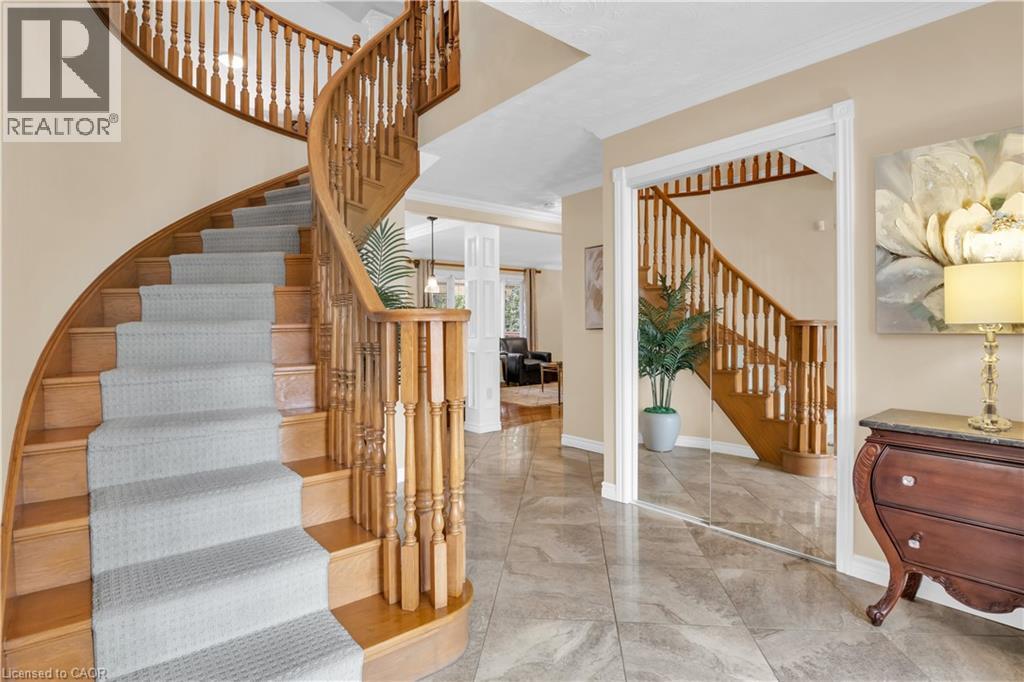 Grand hardwood spiral staircase featuring decorative balusters and light-toned carpet runner - 228 Michener Crescent, Kitchener, ON - Indoor Photo Showing Other Room