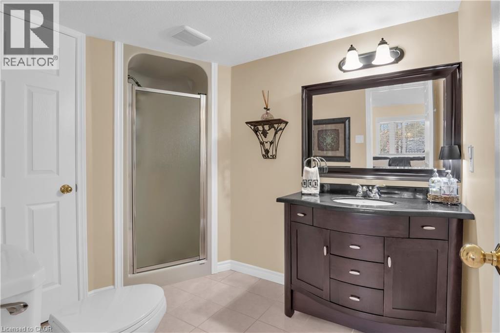 Bathroom featuring a dark wood vanity with an undermount sink, a dark countertop, and an expansive framed mirror - 228 Michener Crescent, Kitchener, ON - Indoor Photo Showing Bathroom