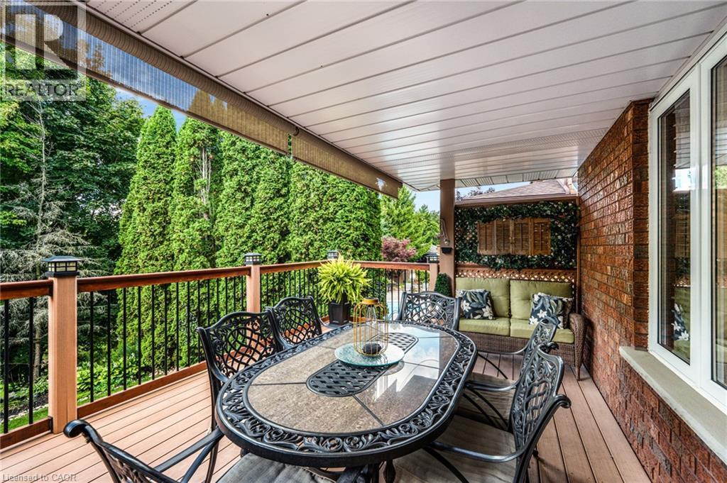 Covered outdoor deck featuring wood-finish flooring, a wood-tone railing with black balusters, and integrated lighting - 228 Michener Crescent, Kitchener, ON - Outdoor With Deck Patio Veranda With Exterior