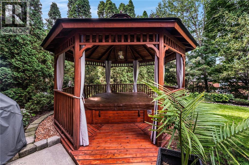 Octagonal wooden gazebo featuring a hot tub, slatted railings, a decorative ceiling, and privacy curtains, set on a multi-level wood-finish deck - 228 Michener Crescent, Kitchener, ON - Outdoor With Deck Patio Veranda