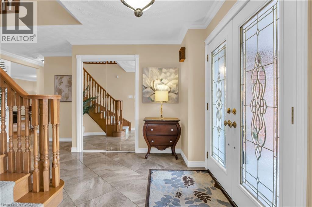 Entryway featuring double doors with decorative glass inserts, crown molding, a wood staircase with balusters, and large format tile flooring - 228 Michener Crescent, Kitchener, ON - Indoor Photo Showing Other Room