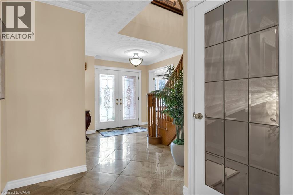 Entryway featuring double doors with decorative glass panels, a circular ceiling medallion with a flush mount light fixture, large format tile flooring, and a wooden staircase with a matching railing - 228 Michener Crescent, Kitchener, ON - Indoor Photo Showing Other Room