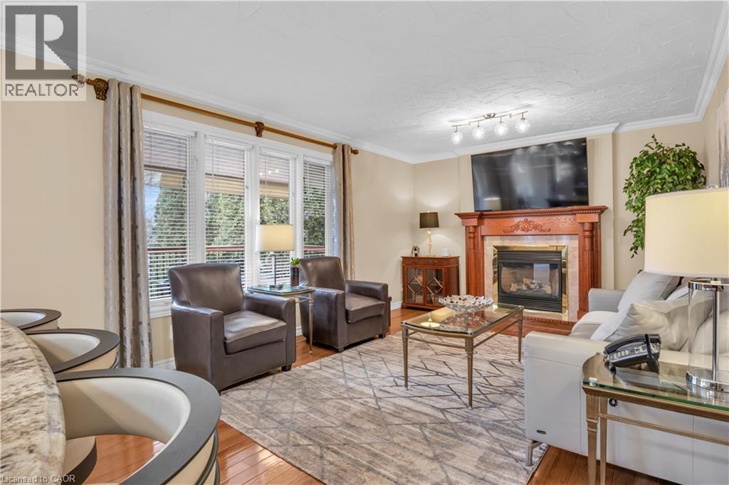 Living area featuring a natural wood fireplace surround with stone accent and a television mounted above - 228 Michener Crescent, Kitchener, ON - Indoor Photo Showing Living Room With Fireplace