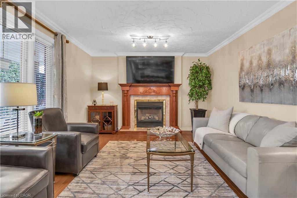 Living area featuring wood-finish flooring, a decorative fireplace with a detailed wood mantel, and crown molding - 228 Michener Crescent, Kitchener, ON - Indoor Photo Showing Living Room With Fireplace