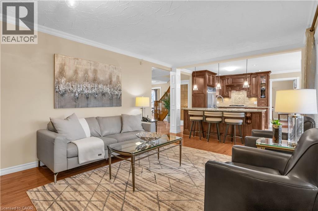 Open-concept living area featuring wood-finish flooring, crown molding, and a kitchen with dark wood cabinetry - 228 Michener Crescent, Kitchener, ON - Indoor Photo Showing Living Room