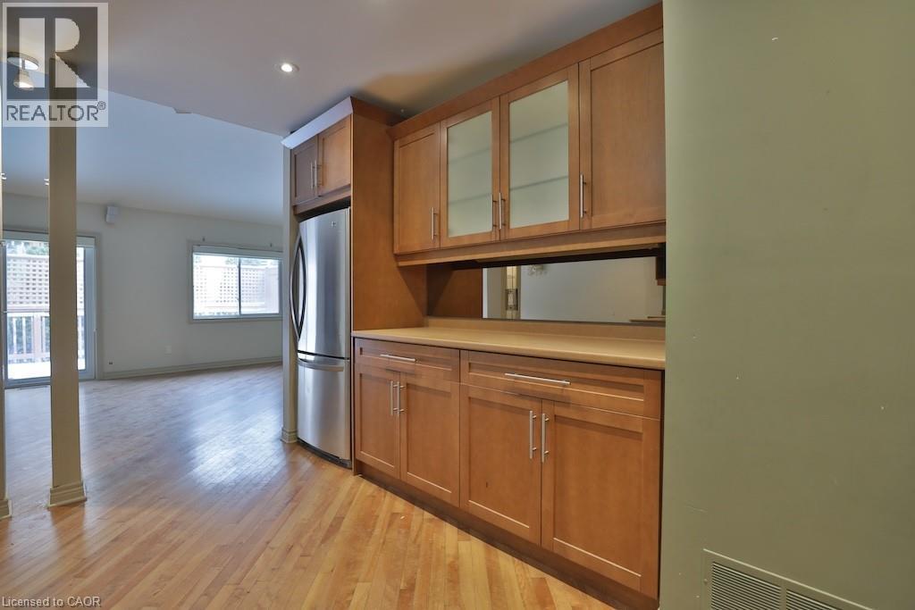 Built-in cabinetry featuring glass-front upper cabinets, a light wood-finish countertop, and integrated stainless steel refrigerator - 7 Gibson Place Unit# 21, St. Catharines, ON - Indoor