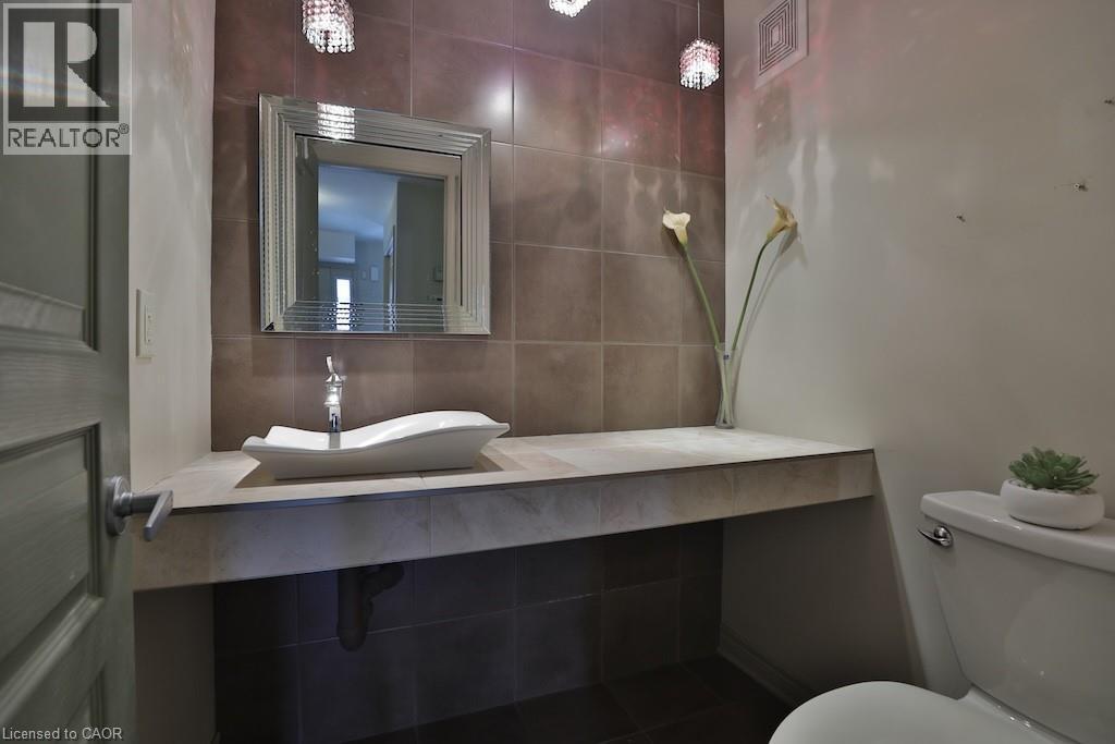 Bathroom featuring a vessel sink, chrome faucet, and a large framed mirror over a built-in vanity - 7 Gibson Place Unit# 21, St. Catharines, ON - Indoor Photo Showing Bathroom