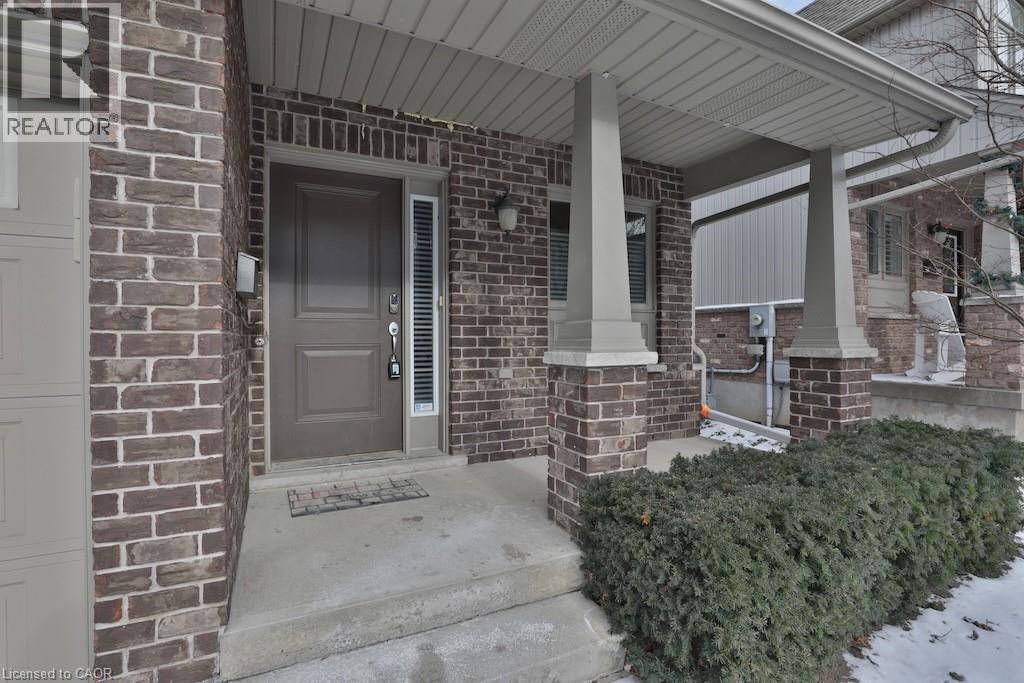 Brick facade residence featuring a covered front porch with substantial columns, a panel-style entry door with a vertical sidelight, and an integrated garage - 7 Gibson Place Unit# 21, St. Catharines, ON - Outdoor