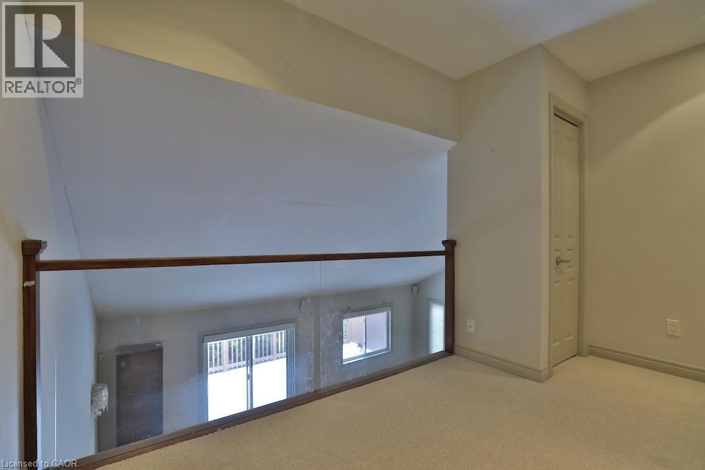 Carpeted loft area featuring a clear glass and wood railing overlooking the lower level - 7 Gibson Place Unit# 21, St. Catharines, ON - Indoor Photo Showing Other Room
