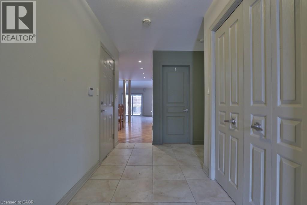 Hallway featuring tile flooring, paneled doors, recessed lighting, and a view into a room with wood-finish flooring and a balcony - 7 Gibson Place Unit# 21, St. Catharines, ON - Indoor Photo Showing Other Room