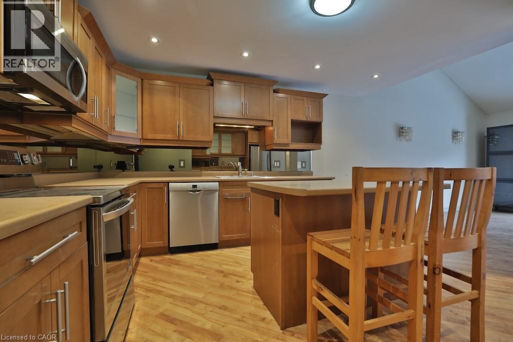 Kitchen featuring wood-finish flooring, light wood cabinetry, stainless steel appliances, and an integrated island - 7 Gibson Place Unit# 21, St. Catharines, ON - Indoor Photo Showing Kitchen