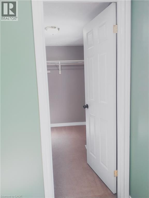 Interior room featuring light green walls, a white paneled door with a black doorknob, and a built-in closet with white shelving - 569 Activa Avenue, Kitchener, ON - Indoor