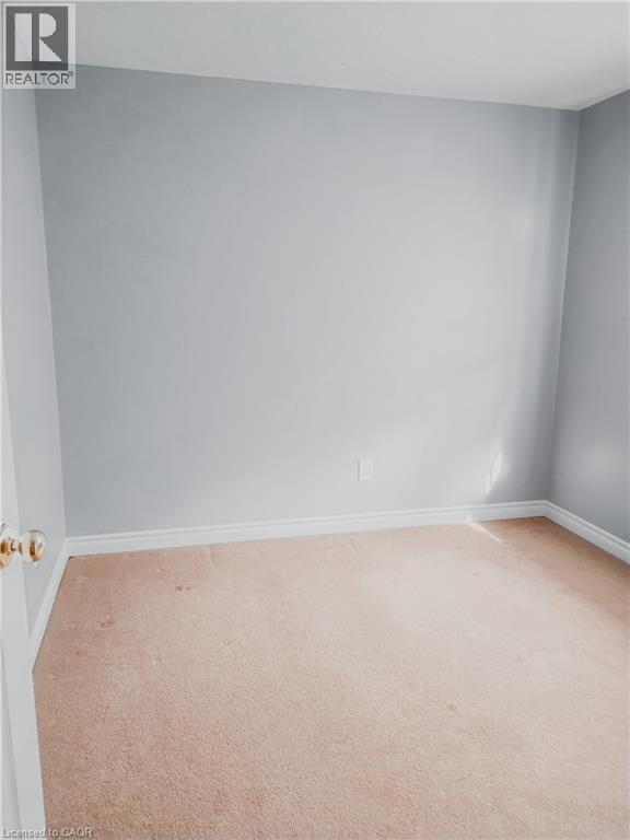 Neutral-toned carpeting extends across the floor, complemented by light gray wall paint and white baseboards - 569 Activa Avenue, Kitchener, ON - Indoor Photo Showing Other Room