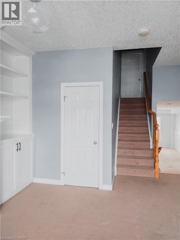 Built-in white cabinetry with open shelving and closed storage, staircase with wood banister, panel doors, and neutral carpeting - 569 Activa Avenue, Kitchener, ON - Indoor Photo Showing Other Room