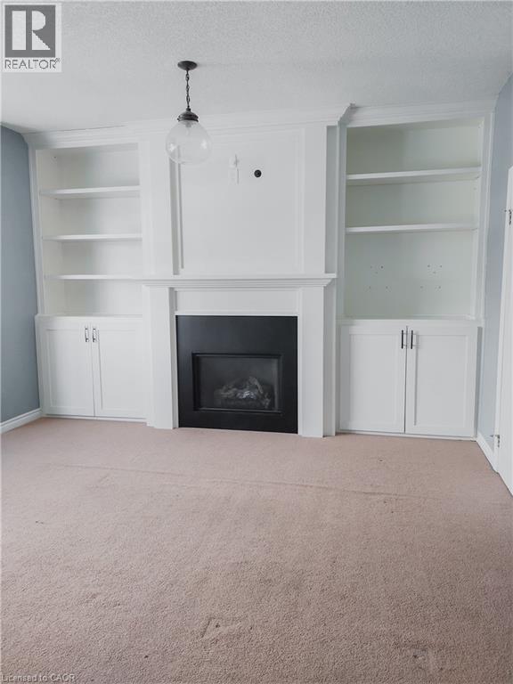 Built-in white cabinetry and shelving flanking a black-framed fireplace with a classic mantelpiece - 569 Activa Avenue, Kitchener, ON - Indoor Photo Showing Living Room With Fireplace