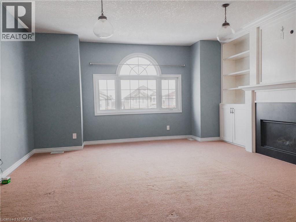 Spacious room featuring a prominent arched window with multiple panes - 569 Activa Avenue, Kitchener, ON - Indoor Photo Showing Other Room With Fireplace