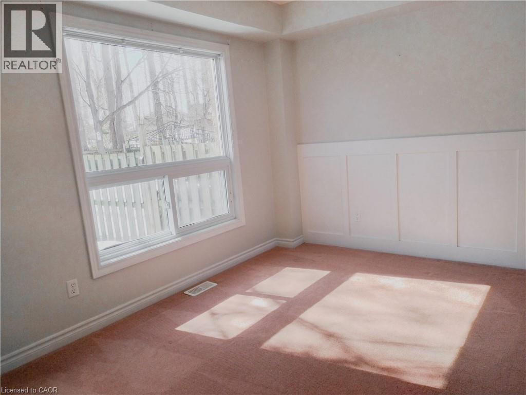 Spacious room featuring a large window, board and batten wall detailing, light-colored walls, base molding, and carpet flooring - 569 Activa Avenue, Kitchener, ON - Indoor Photo Showing Other Room