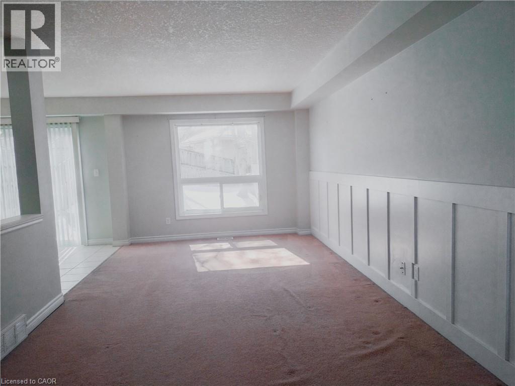 Carpeted living area with wainscoting detail and a large window providing ample natural light - 569 Activa Avenue, Kitchener, ON - Indoor Photo Showing Other Room