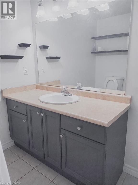 Bathroom vanity with a light-colored countertop, integrated sink, and dark cabinetry with silver-toned hardware - 569 Activa Avenue, Kitchener, ON - Indoor Photo Showing Bathroom