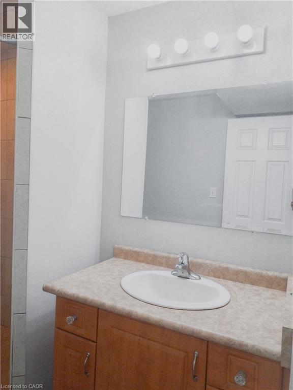 Bathroom vanity with a light wood-finish cabinet, integrated oval sink, and a speckled countertop - 569 Activa Avenue, Kitchener, ON - Indoor Photo Showing Bathroom