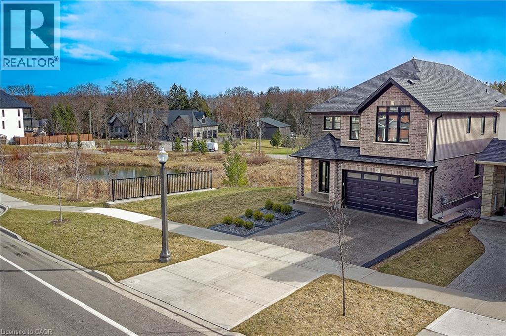 View of front of property featuring concrete driveway, a shingled roof, a front yard, an attached garage, and brick siding - 477 Blair Creek Drive, Kitchener, ON - Outdoor