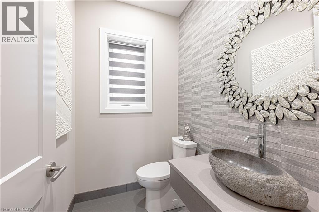 Half bathroom with baseboards, an accent wall, tile walls, toilet, and tile patterned floors - 477 Blair Creek Drive, Kitchener, ON - Indoor Photo Showing Bathroom