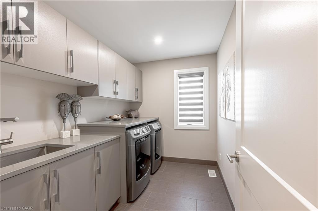 Clothes washing area featuring baseboards, light tile patterned floors, independent washer and dryer, cabinet space, and a sink - 477 Blair Creek Drive, Kitchener, ON - Indoor Photo Showing Laundry Room
