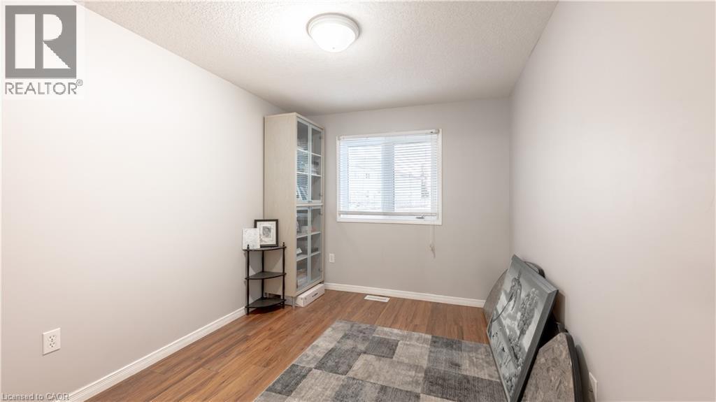 Unfurnished room with a textured ceiling, wood finished floors, and baseboards - 85 Bankside Drive Unit# E34, Kitchener, ON - Indoor