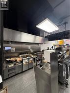 Commercial kitchen featuring a large stainless steel exhaust hood and a suspended rectangular light fixture -