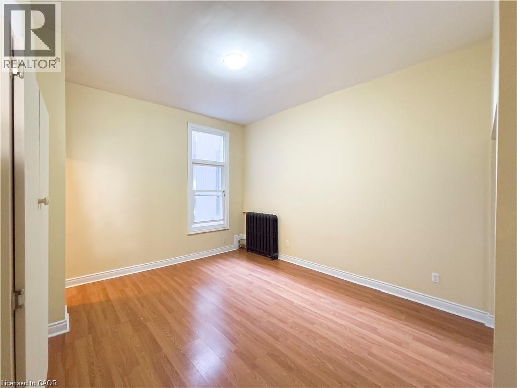 Interior room with light wood-finish flooring and a central ceiling light fixture - 85 King Street W, Kitchener, ON