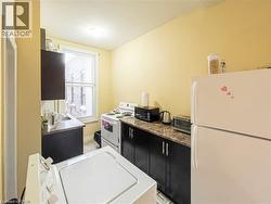 Compact kitchen featuring a white top-load washing machine, white range, and a white refrigerator -