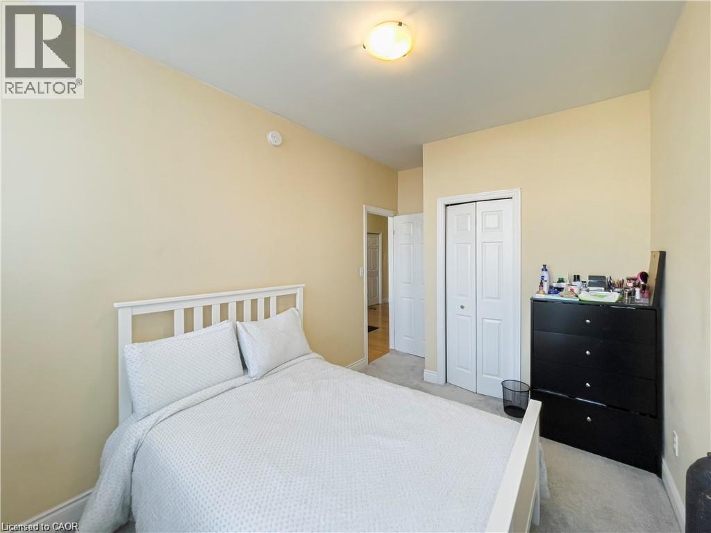 Carpeted bedroom featuring a flush-mount ceiling light, light-toned walls, and a bi-fold closet door - 85 King Street W, Kitchener, ON