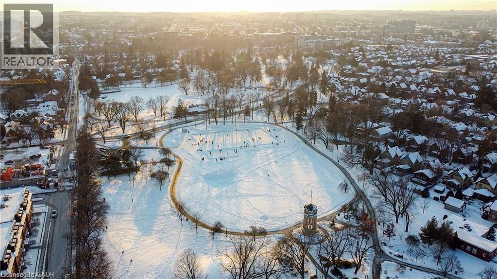 Expansive snow-covered parkland featuring a winding pathway, numerous trees, and a central tower structure - 85 King Street W, Kitchener, ON