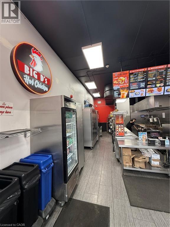 Commercial kitchen space featuring stainless steel refrigeration units, wood-finish flooring, recessed ceiling lights, and wall-mounted shelving - 85 King Street W, Kitchener, ON