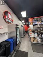 Commercial kitchen space featuring stainless steel refrigeration units, wood-finish flooring, recessed ceiling lights, and wall-mounted shelving -