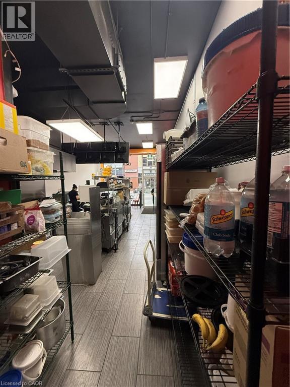 Commercial kitchen with gray wood-finish tile flooring, recessed and suspended ceiling lighting, and exposed ductwork - 85 King Street W, Kitchener, ON