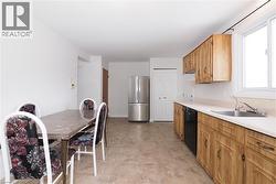 Open-concept kitchen and dining area featuring light-toned cabinetry, stainless steel refrigerator, and a window above the sink -